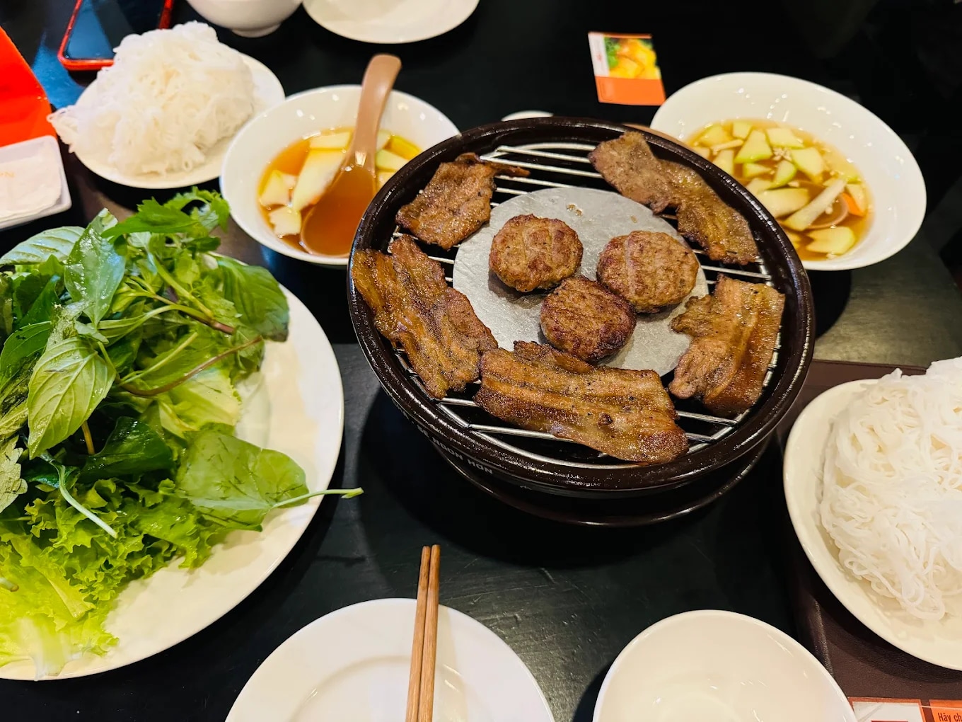 The grilled meat is kept warm on a mini charcoal stove placed right at the table 